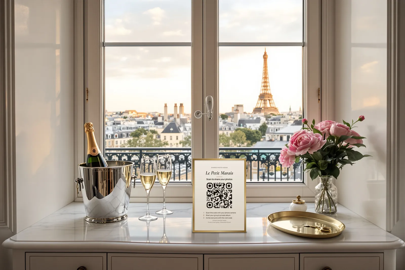 A framed card with a QR code on a marble console between two glasses of champagne and a brass tray, with the Eiffel Tower in the window
